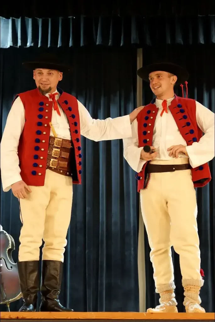 Dwaj mężczyźni w strojach ludowych górali dorzecza Soły, którzy stoją na scenie uśmiechając się.