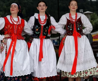 Grupa trzech Góralek Żywieckich z grupy śpiewaczej wchodzącej w skład oferty. Ubrane w tradycyjne stroje, występujące na dużej scenie.